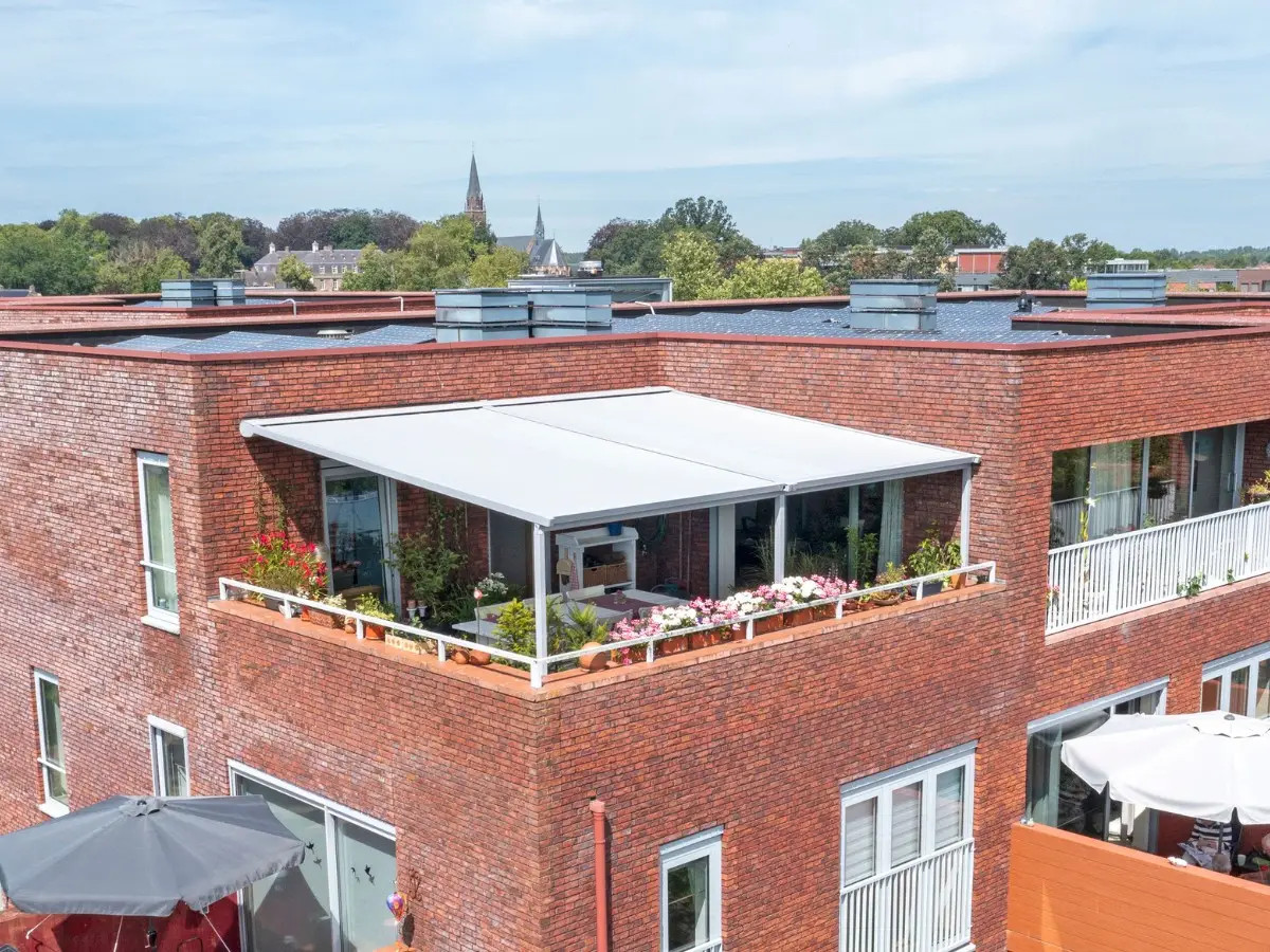 Impressie van een appartement met een groot terras, voorzien van een pergola zonwering.