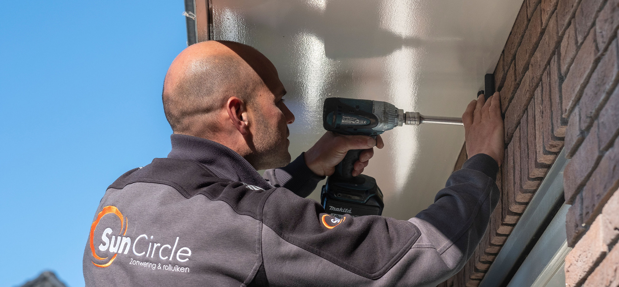 Impressie van iemand die zonwering aan het monteren is.